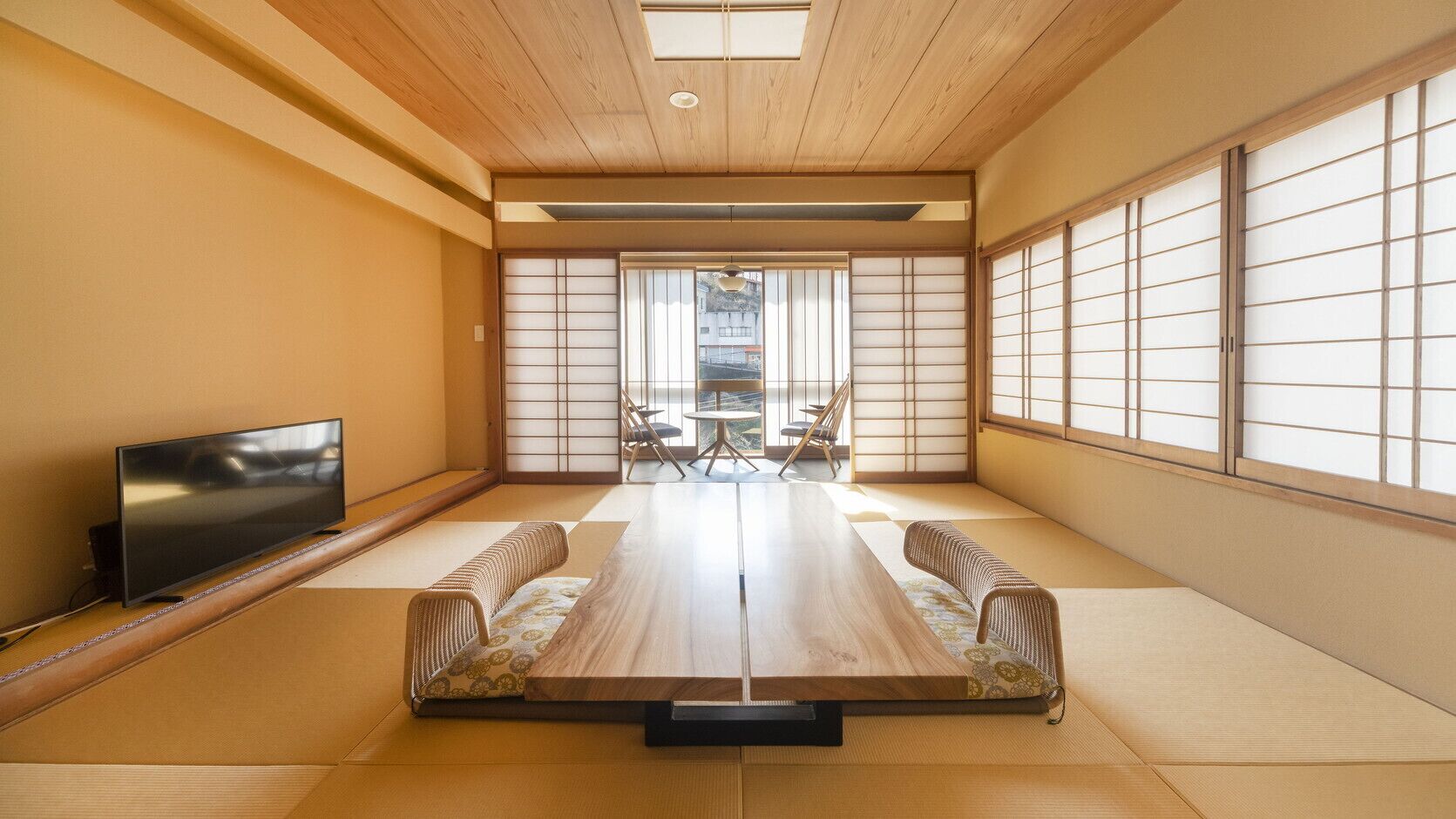 A tatami mat room with a TV, a low table, and sliding doors.
