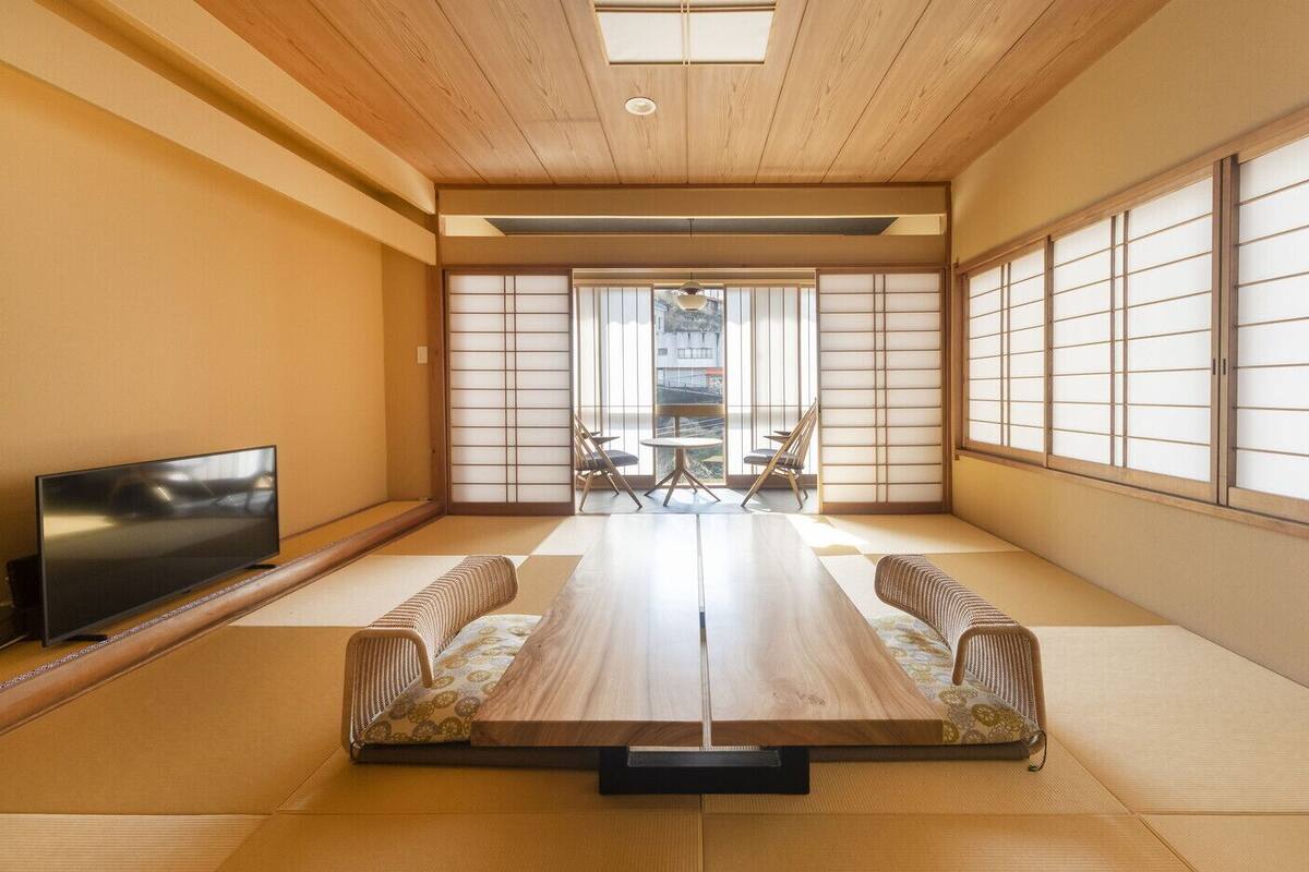 A tatami mat room with a TV, a low table, and sliding doors.
