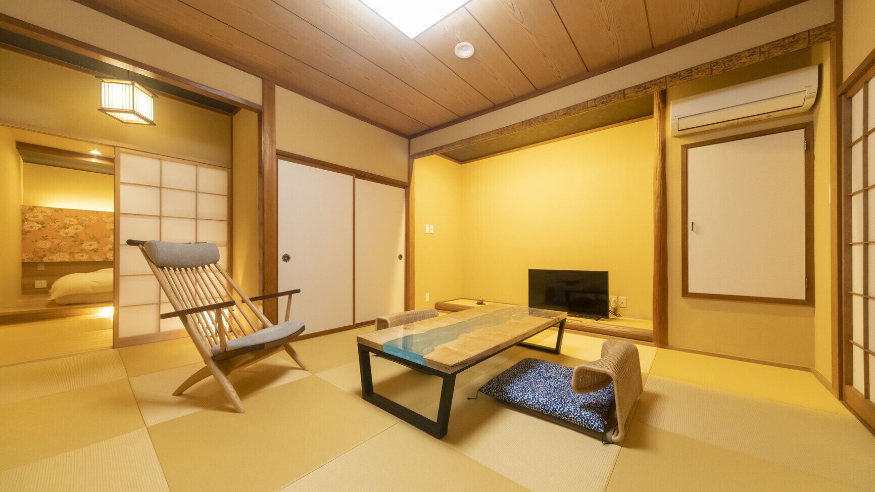 A traditional Japanese room with tatami flooring, a low table, a television, and sliding doors.