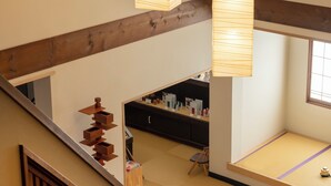 Un interior amplio con una escalera de madera, una zona de cocina y farolillos de papel colgantes.