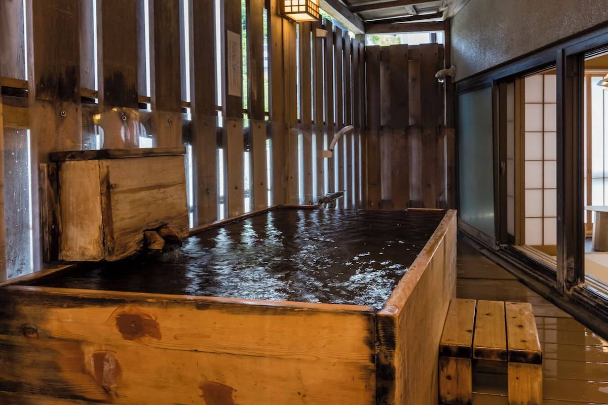 A traditional Japanese onsen with wooden benches and a wooden bath.
