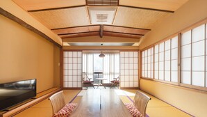 Una habitación japonesa tradicional con suelo de tatami, una mesa baja y puertas correderas.