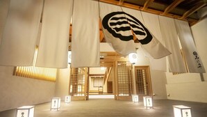 Un interior japonés tradicional con suelo de tatami, puertas correderas y banderines colgantes.