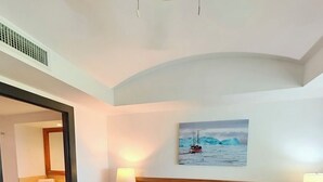 Hotelkamer met een groot bed, twee nachtkastjes met lampen, een schilderij van een boot op het water en een spiegel in de hoek.