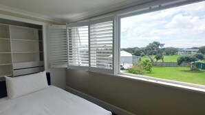 Un dormitorio con un ventanal grande, una cama y un armario empotrado.