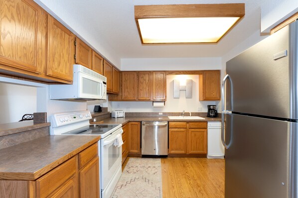 A modern kitchen with wooden cabinets, stainless steel appliances, and a built-in microwave.