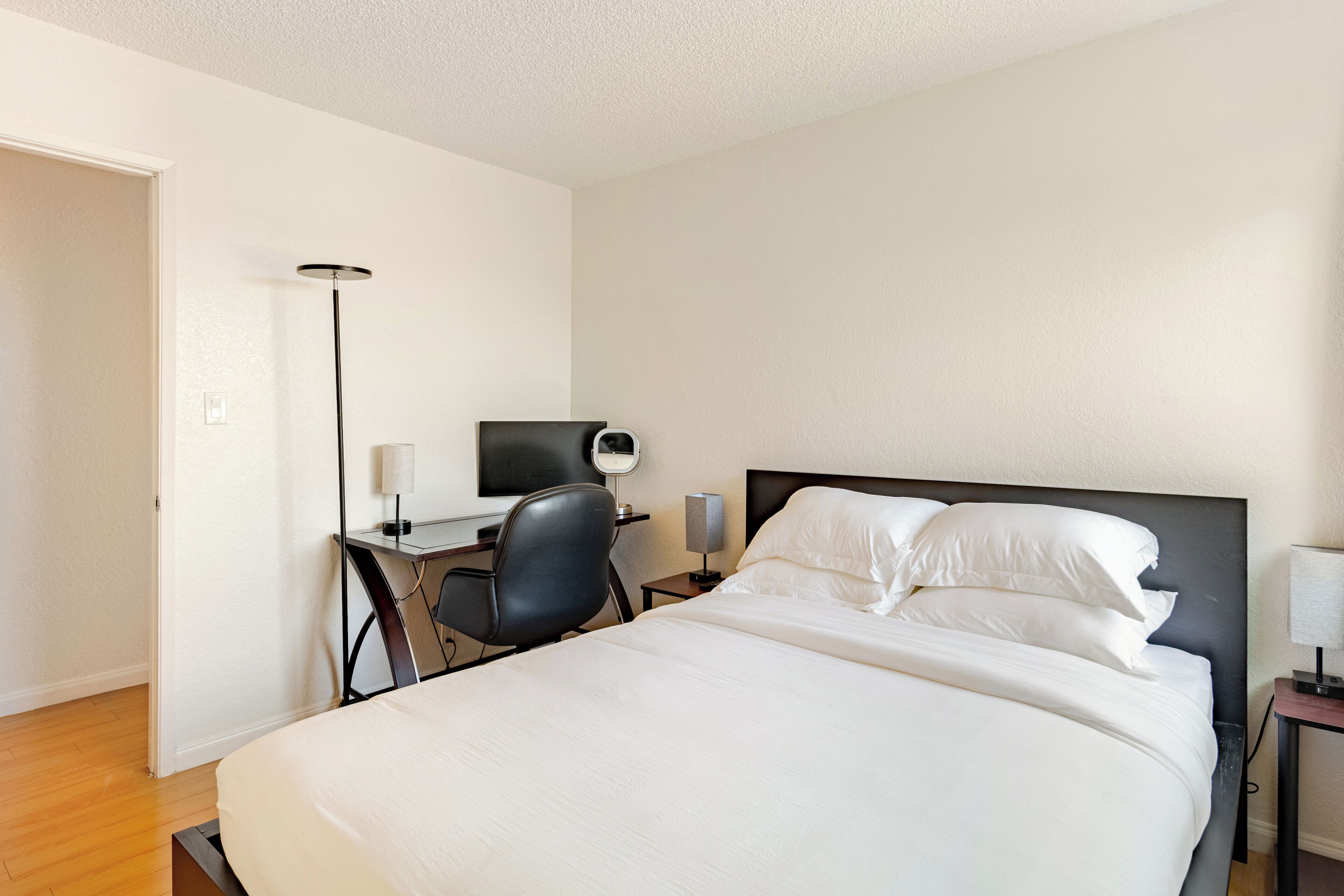 Hotellihuone, jossa on sänky, työpöytä, tuoli ja lamppu.