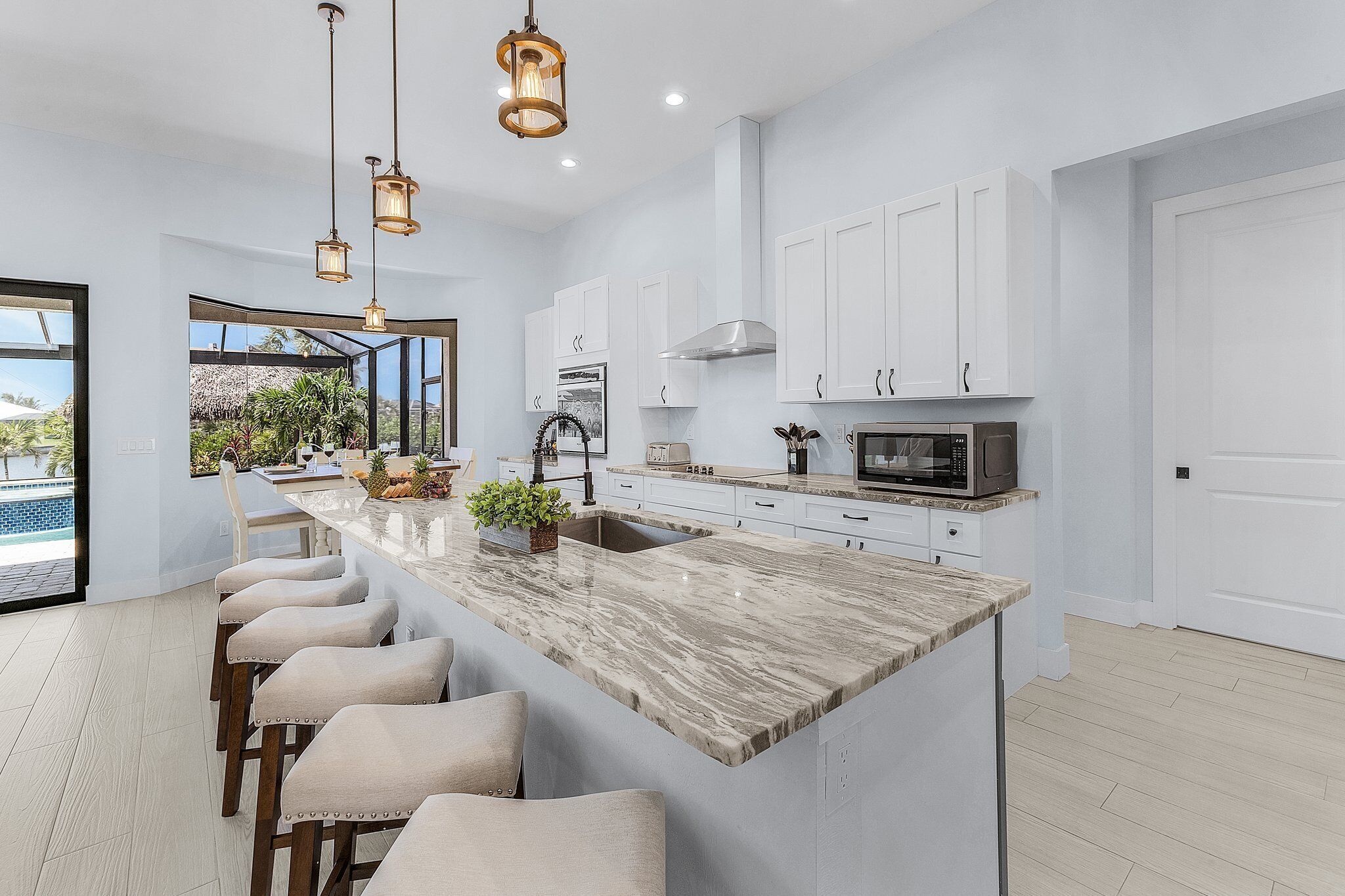 A modern kitchen with white cabinets, a marble island, and bar stools.