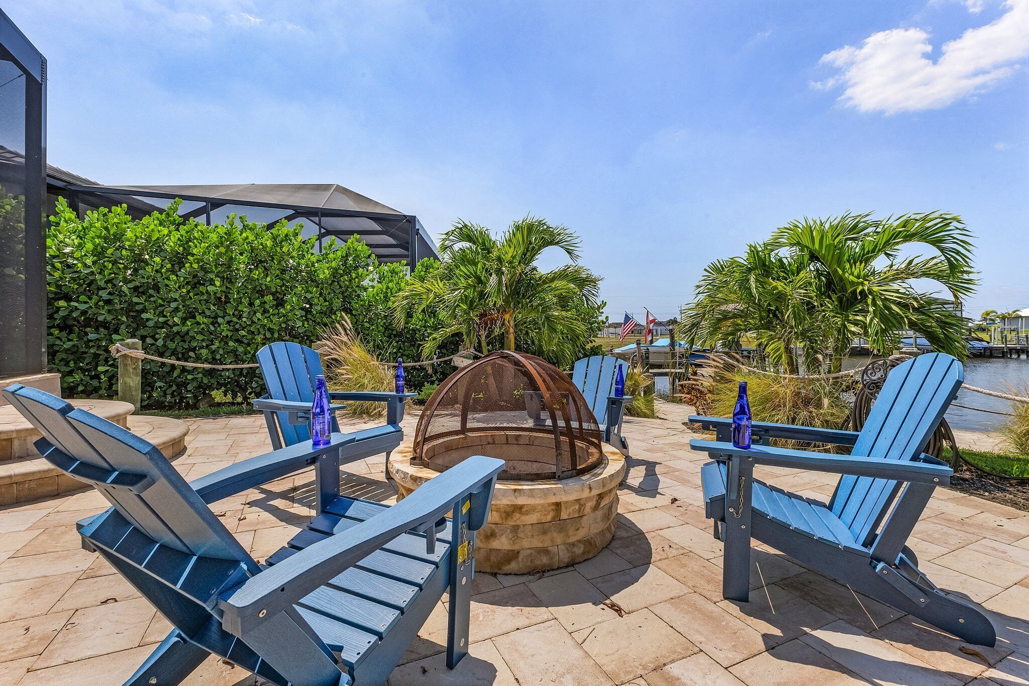 An outdoor seating area with Adirondack chairs, a fire pit, and a view of the water.