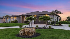 A modern house with a well-maintained lawn and a large rock centerpiece.