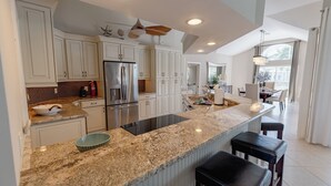 A spacious kitchen with white cabinets, a granite countertop, and a stainless steel refrigerator. - Waterfront, Private Pool, Walk to Tigertail Beach, Best of Marco! (Marco Island)