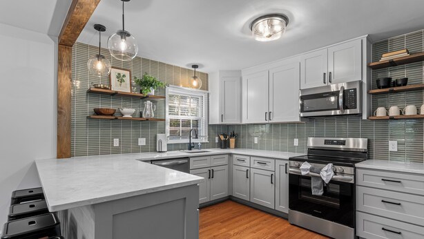 A modern kitchen with white cabinets, a stainless steel microwave, and a built-in oven.