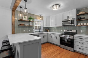 Una cocina moderna con armarios blancos, un microondas de acero inoxidable y un horno empotrado.