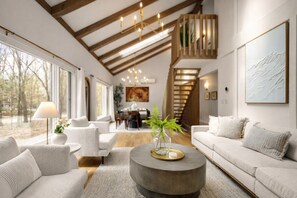 Un ampio soggiorno con soffitto alto, una scala e un'area pranzo.