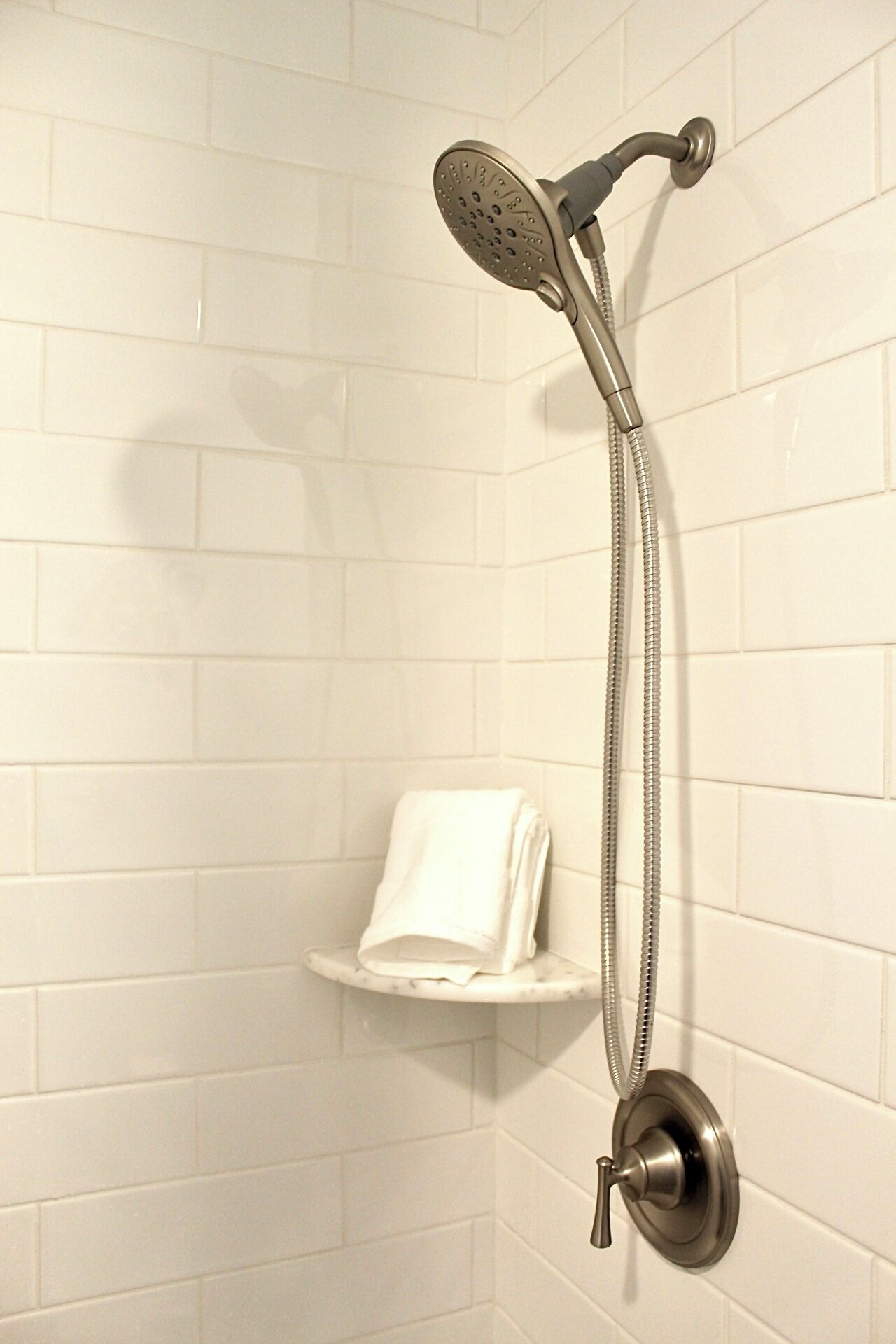 Une douche équipée d’un pommeau de douche à main et de commandes murales.