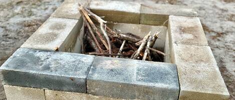 A concrete fire pit with logs inside, surrounded by a square stone border.
