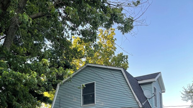 A two-story house with a porch, a front door, and a small window.