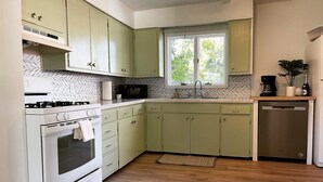 A kitchen with light green cabinets, a white stove, a microwave, and a dishwasher.