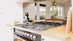 A modern kitchen with a gas stove, oven, and a wooden countertop. - Evans Head Beach House - Entertainer (Evans Head)