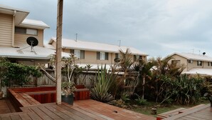 A residential area with multiple houses, a wooden deck, and various tropical plants. - Evans Head Beach House - Entertainer (Evans Head)