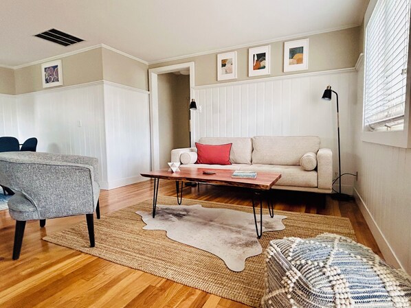 Un salon avec un canapé, une table basse, un tapis et un fauteuil.