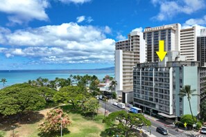 A multi-story hotel with a view of the ocean, surrounded by greenery.