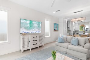 A modern living room with a large TV, a sofa, and a dining area.
