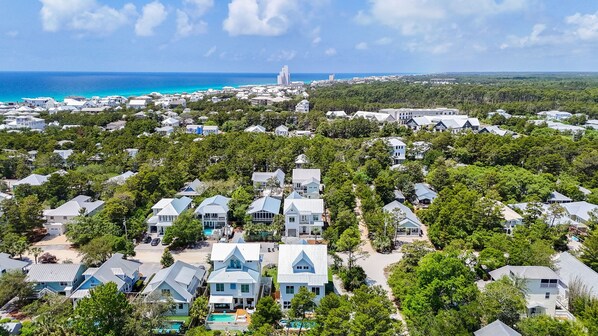 A coastal residential area with houses surrounded by dense greenery and a clear view of the ocean. - Shore Thing | Private Pool | Walk to the beach | Bike to Seaside | Brand New Construction and Decor (Santa Rosa Beach)