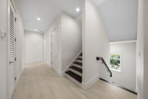 A modern interior with a staircase, white walls, and a window with a view of greenery. - Shore Thing | Private Pool | Walk to the beach | Bike to Seaside | Brand New Construction and Decor (Santa Rosa Beach)