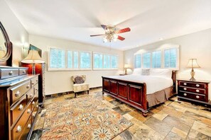 A bedroom with a bed, dresser, nightstand, chair, and a ceiling fan.