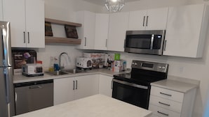Una cocina moderna con armarios blancos, electrodomésticos de acero inoxidable y una encimera de tono claro.