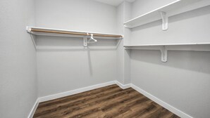 A corner closet with white walls, wooden flooring, and white shelving units. - Spacious & Cozy 3Bdroom ~ Party/Events Welcome (Houston)