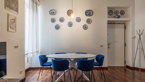 Un comedor con una mesa redonda y sillas azules, rodeado de piso de madera y paredes blancas.