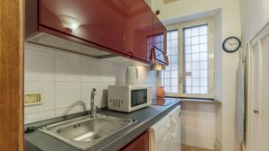 A kitchen with a stainless steel sink, a microwave, and a window with a view.