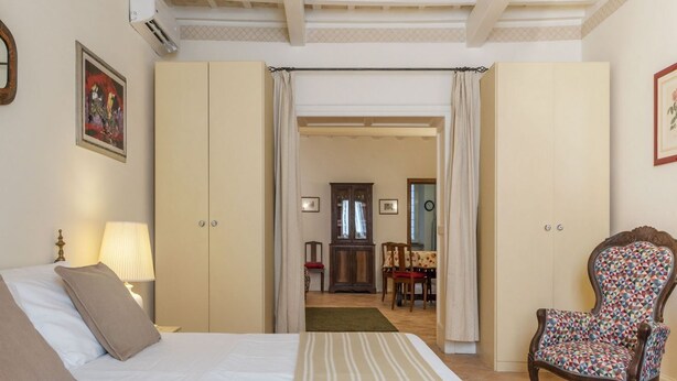 A bedroom with a bed, a chair, and a wardrobe.