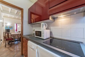 A kitchen with a microwave, dishwasher, and a dining area with a table and chairs. - Fontanella Borghese 66 (Roma)