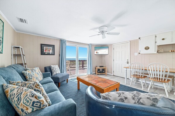A living room with a sofa, a coffee table, a TV, and a ceiling fan.