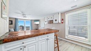 A kitchen with white cabinets, a wooden countertop, and a ceiling fan. - CHARMING COTTAGE ON THE BEACH! (Gulf Shores)