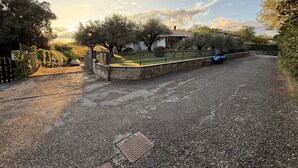 A gravel driveway leading to a gated property with a house and trees.