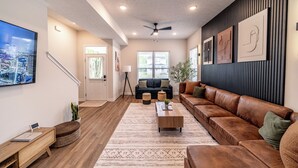 A modern living room with a brown leather sofa, a wooden coffee table, and a large flat-screen TV. - Game Room! Modern 3BR 2.5BA New Build Luxury—Near Downtown Cleveland! (Cleveland)