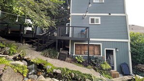 A multi-level house with a balcony, a small waterfall, and a garden area with rocks and plants. - 7 min to downtown! Retreat for 2 on Queen Anne Hill w/Rooftop Deck & Ocean View. (Seattle)
