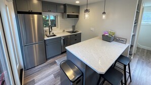 A modern kitchen with grey cabinets, stainless steel appliances, a marble countertop, and pendant lighting. - 7 min to downtown! Retreat for 2 on Queen Anne Hill w/Rooftop Deck & Ocean View. (Seattle)