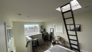 A bedroom with a loft desk, a ladder, a bed, and a view of the outside. - 7 min to downtown! Retreat for 2 on Queen Anne Hill w/Rooftop Deck & Ocean View. (Seattle)