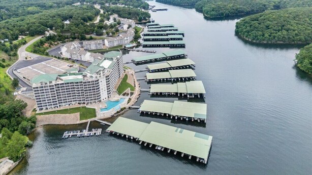 Hotel aan de rivier met meerdere boten afgemeerd, een zwembad en een groot gebouw met een groen dak.