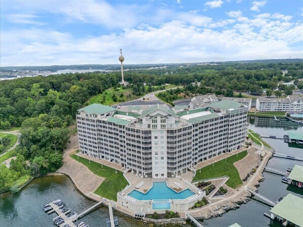 A large hotel with a central courtyard and a swimming pool, surrounded by water and greenery.