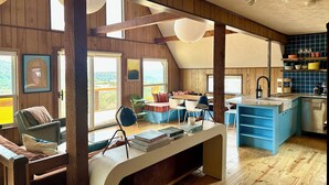 Una habitación acogedora con paredes de madera, un comedor y una cocina con armarios azules.