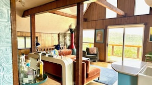 Un interior acogedor de cabaña con paredes de madera, una zona de comedor, un sofá y vistas al exterior.