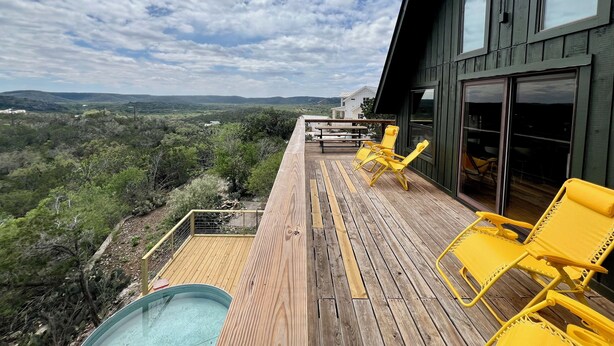 Terraza de madera con sillas amarillas y piscina, con vistas a un paisaje pintoresco.