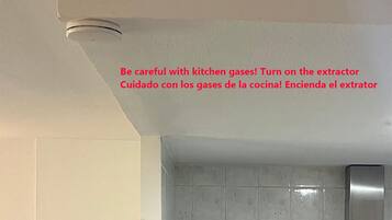 Een keuken met een Bosch koelkast, een grijze betegelde achterwand en een roestvrijstalen afzuigkap.