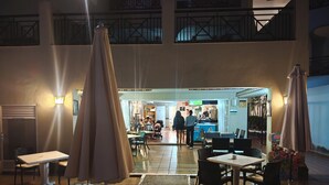 An indoor dining area with tables and chairs, a counter with staff, and a view of the outside balcony.
